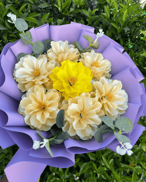 Ramo de flores eternas, compuesto por 7 dalias amarillas brillantes, elegantemente envuelto en papel coreano de color lila.